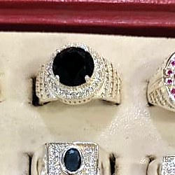 Men's ring with an oval black onyx style stone surrounded by small clear stones