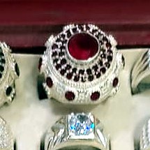 Men's ring with a round red stone surrounded by a halo of small clear stones